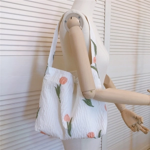 Détail du sac cabas blanc à fleurs de tulipes sur un mannequin en bois clair