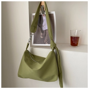 Detail view of olive green fabric Hobo bag hanging on a wall hook in a home setting
