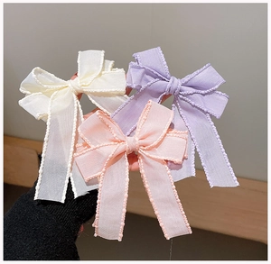 Detailed view of layered translucent bow hair clips with pearl-edge finish in pastel colors