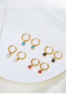 Detail view of gold titanium hoop earrings with colorful round zirconia pendants