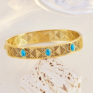 Bohemian gold openwork cuff bracelet featuring oval blue turquoise on stone background