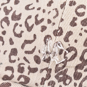 Dettaglio del tessuto in cotone leopardato vintage con finitura invecchiata e fori sfrangiati
