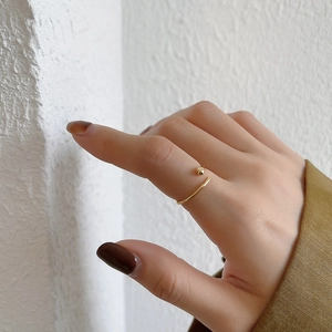 Detail of adjustable gold-plated droplet ring worn on hand with minimalist bead design