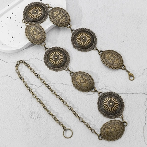 Détail d'une ceinture en métal bronze vintage avec disques gravés et fermoir mousqueton