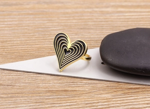 Detail of 18K gold plated heart ring with black enamel layers on a natural wood surface