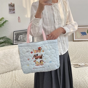 Detail of blue quilted cotton bag featuring cute sausage dog embroidery and pink handles