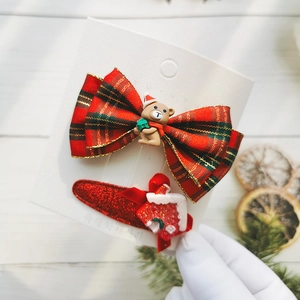 Close-up of Christmas bow hair clip with bear and gingerbread house hairpins