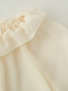 Dettaglio ravvicinato dello scollo con volant su un elegante completo in chiffon crema