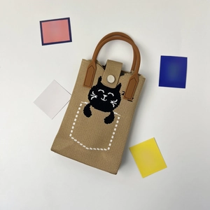 Detail of the knit phone bag showing light khaki fabric with a black cat design