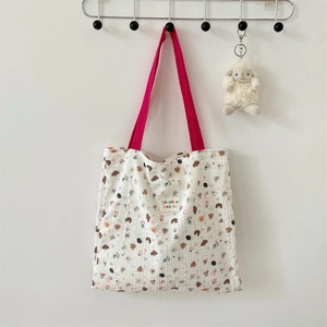 Close-up of cream textured tote bag with colorful cartoon bear and puppy patterns