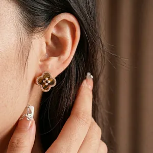 Elegant clover earrings with tiger eye stone and small white diamonds worn by a model