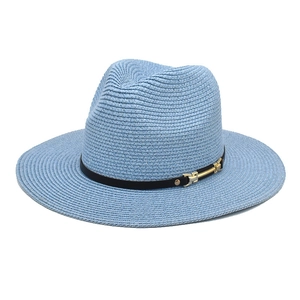 Close-up of light blue straw fedora weave texture with black ribbon and gold buckle