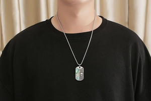Close-up of a men's titanium steel military tag pendant with skull and abalone shell