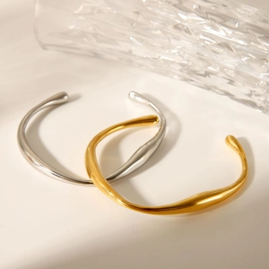 Close-up of gold and silver irregular wavy stainless steel bracelets with a polished finish