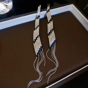 Detailed close-up of long silver fringe earrings with black beads on a tray