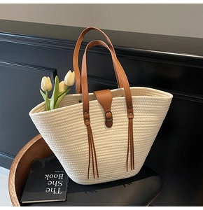 Detail of woven tote bag with brown leather straps and tassel on a designer chair