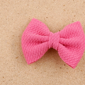 Close-up of pink textured fabric bow hair clip on a natural cork background