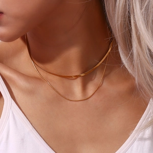 Detail of layered gold double strand necklace featuring a flat snake chain on model