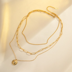 Detail of layered gold stainless steel necklace with sunburst pendant on silk