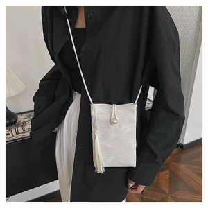 Détail du sac de téléphone blanc crème avec boucle en perle et gland en soie