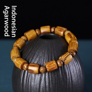 Bracciale in legno di agar indonesiano con venature naturali su vaso di ceramica