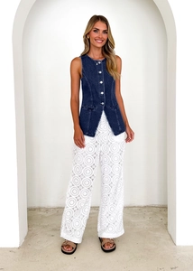 Detail of vintage denim vest paired with white hollow lace wide-leg trousers on a model