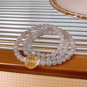 Detailed macro view of moonstone beaded bracelet with yellow floral bead and silver accents