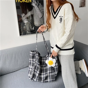 Detail of plaid canvas tote bag with a white flower charm and classic checkered pattern
