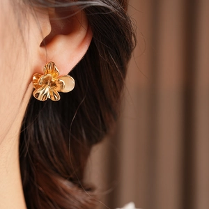 Detailed close-up of a vintage brushed gold flower earring with a central opal inlay
