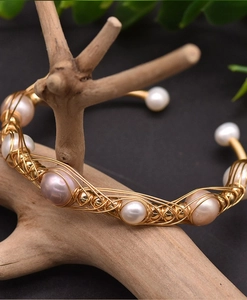 Detail of handcrafted gold wire wrap bracelet with white and pink freshwater pearls