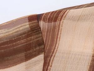 Dettaglio delle strisce a pennellate marroni e beige su tessuto in chiffon leggero