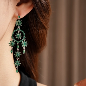 Close-up of green crystal floral tassel earrings worn by a model in soft lighting