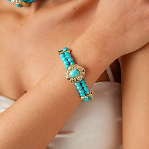 Close-up of double-layer turquoise beaded bracelet with gold vintage sunflower charm