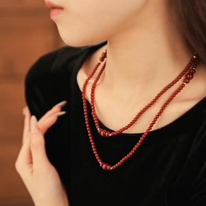 Dettaglio della collana a doppio strato in perle di vetro rosso scuro e distanziatori dorati