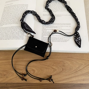 Detail of bohemian mini bag with ethnic floral strap and wooden bead accents on book