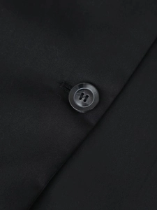Détail du tissu en sergé noir et du bouton en résine sur une élégante robe courte