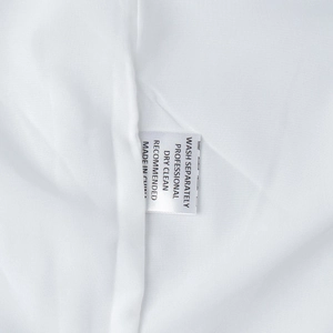 Detailed view of the wash care label on a white cotton linen dress with washing instructions