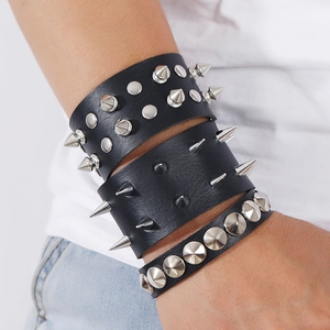 Detail of punk black leather bracelets featuring silver metallic studs and spikes on arm