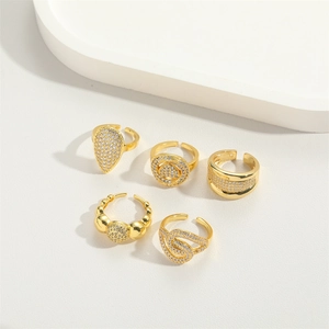 Detailed view of five adjustable gold rings set with zircon in minimalist white tray