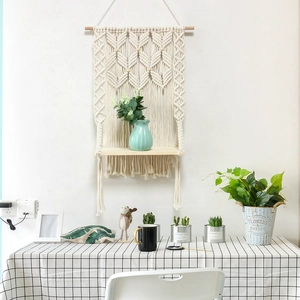 Detail of macrame wall hanging shelf featuring beige cotton rope and wooden plant stand