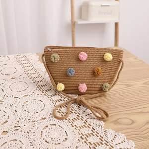 Close-up of handmade straw crossbody bag featuring colorful pom-poms and fine texture