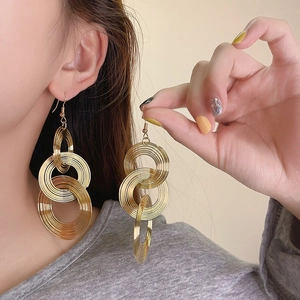 Detailed macro shot of vintage-style gold multi-layered circular drop earrings worn by a model