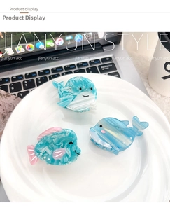 Close-up of three ocean-themed acetate hair claws in whale and dolphin shapes