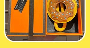Détail d'un porte-clés beignet en cuir avec cordon dans un coffret cadeau orange