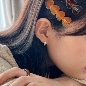 Detail of 925 sterling silver earring with white pearl and gold bead on model