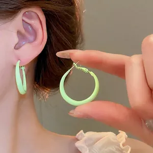 Minimalist green glossy hoop earrings shown worn on ear for a stylish commute look