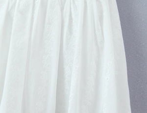 Macro shot of white lace dress fabric with delicate vertical leaf embroidery detail