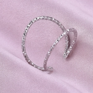 Macro shot of silver dual-layer open ring with geometric hammered texture on silk background