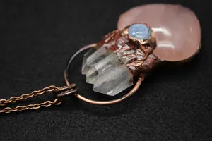 Macro shot of vintage copper pendant featuring pink quartz heart and clear crystal cluster
