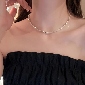 Nahaufnahme eines silbernen Chokers mit weißen Perlen auf einer eleganten Gliederkette